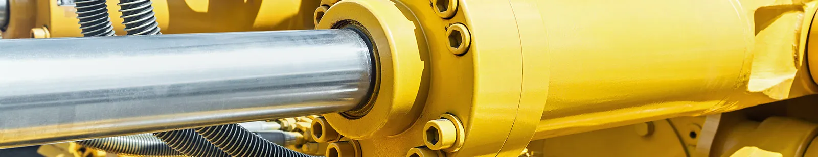 Close-up of a chrome hydraulic cylinder rod on yellow heavy equipment